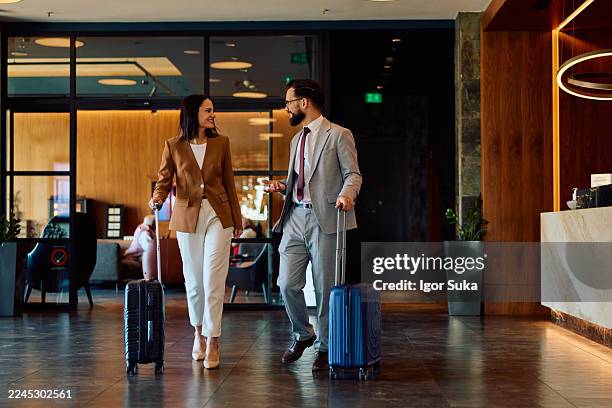 business colleagues arriving at hotel lobby discussing work - business class imagens e fotografias de stock