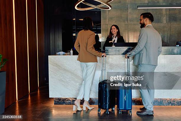 couple checking in at hotel reception desk - bus boy stock pictures, royalty-free photos & images