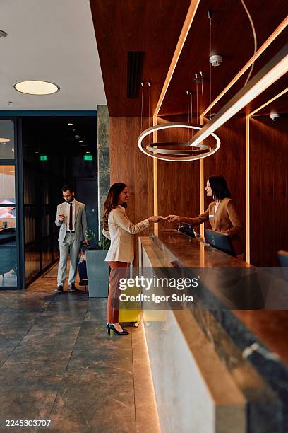 female guest checking in at modern hotel reception desk - reception bildbanksfoton och bilder