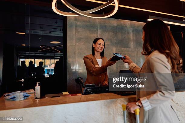 woman making contactless smartphone payment checking into hotel - reception bildbanksfoton och bilder