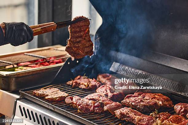chef checks the doneness of the steak. close-up of a grilled steak in tongs - grillen stock-fotos und bilder