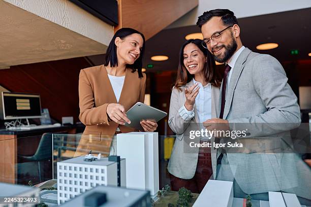 business professionals discussing architectural model with digital tablet - real estate developer stock pictures, royalty-free photos & images
