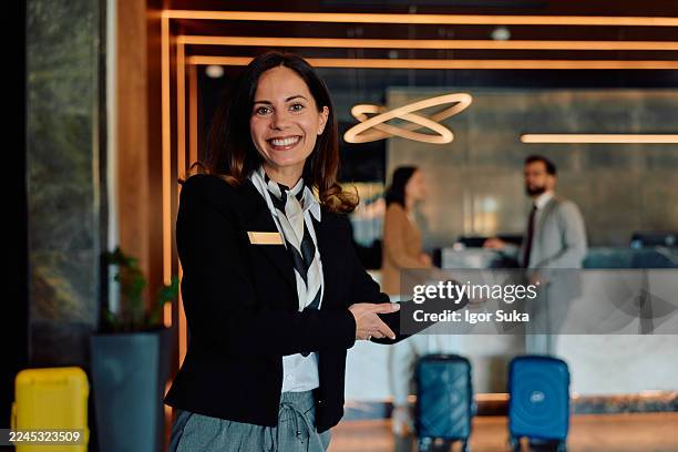 sorridente receptionist dell'hotel che accoglie gli ospiti nella hall - ospite foto e immagini stock