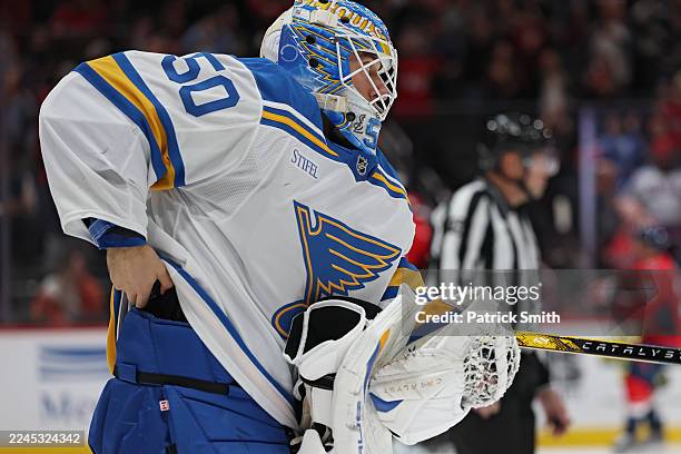 Goalie Jordan Binnington of the St. Louis Blues attempts to hide the puck in his pads of NHL career goal 900 by Alex Ovechkin of the Washington...