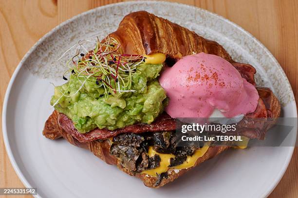 avocado and bacon croissant with soft-boiled egg - plat stockfoto's en -beelden