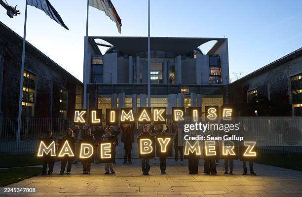 Climate activists from Fridays for Future hold up illuminated letters that read: "Climate Crisis Made by Merz" outside the Chancellery ahead of...