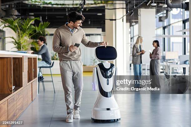 uomo che interagisce con un robot umanoide in un ufficio moderno - robotica foto e immagini stock