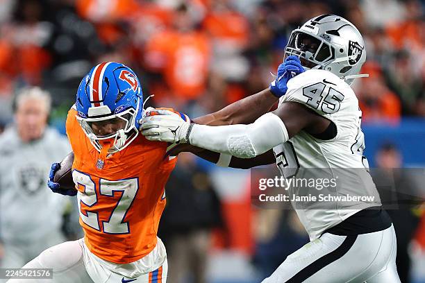 Dobbins of the Denver Broncos stiff arms Devin White of the Las Vegas Raiders during the second quarter in the game at Empower Field At Mile High on...