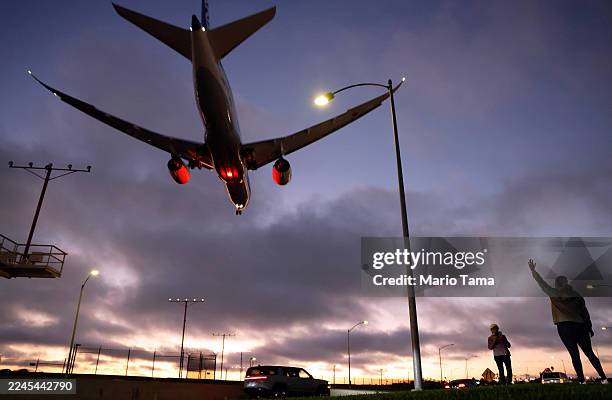 People take photos as a plane lands at Los Angeles International Airport on November 6, 2025 in Los Angeles, California. The FAA will be reducing...