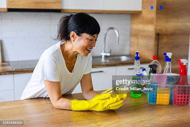 woman reading ingredients on cleaning product label - luva para lavar louça imagens e fotografias de stock