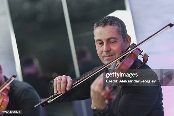 violinist playing in a live music session with focused expression and bow motion - classical musician stock pictures, royalty-free photos & images