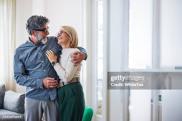 warm embrace between couple in living room showing happiness, connection, and shared moments - pair stock pictures, royalty-free photos & images