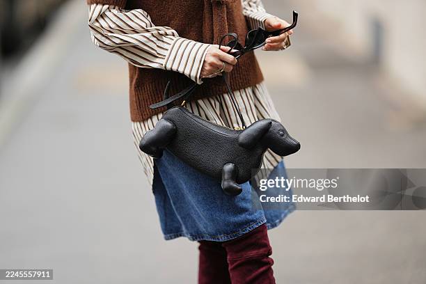 Heart Evangelista wears a brown wool sweater layered over a beige and brown striped oversized button-up shirt with a black velvet bow at the collar,...