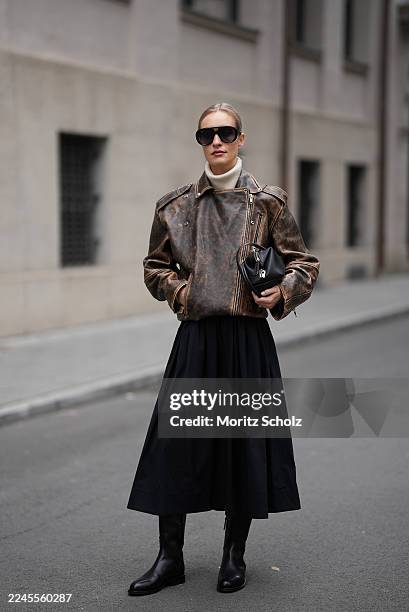Marlies Pia Pfeifhofer is seen wearing a distressed brown leather biker jacket with a stand-up collar and asymmetrical zip-up front by H&M Studio; a...
