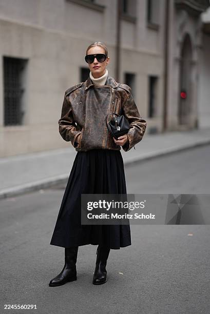 Marlies Pia Pfeifhofer is seen wearing a distressed brown leather biker jacket with a stand-up collar and asymmetrical zip-up front by H&M Studio; a...
