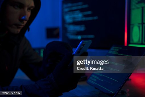Hooded hacker stealing data using a smartphone. Hooded hacker stealing data using a smartphone.