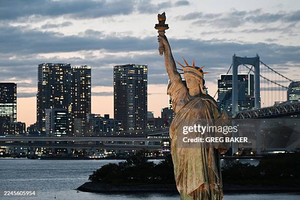 The Tokyo city skyline is seen behind a replica of the Statue of Liberty in the Odaiba area of Tokyo on November 11, 2025.