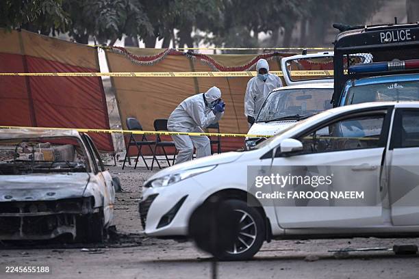 Forensic experts examine a car after a suicide blast outside the district court in Islamabad on November 11, 2025. The Pakistani Taliban claimed a...
