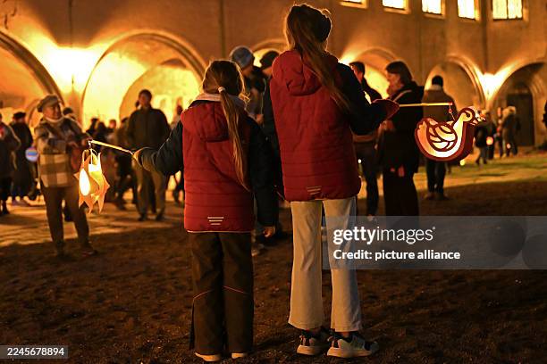 November 2025, Saxony-Anhalt, Halle: Two girls stand in the courtyard of Moritzburg Castle with their lanterns. In the Catholic Church, November 11...