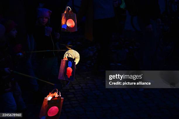 November 2025, Saxony-Anhalt, Halle: On St. Martin's Day, people with lanterns walk through Halle's city center. Accompanied by trumpets, the...