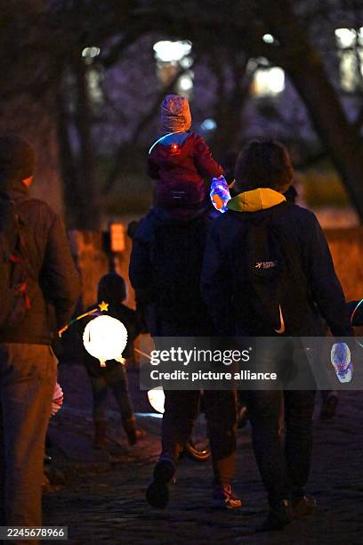 November 2025, Saxony-Anhalt, Halle: On St. Martin's Day, people with lanterns walk through Halle's city center. Accompanied by trumpets, the...