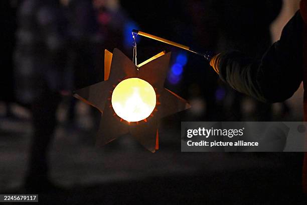 November 2025, Saxony-Anhalt, Halle: On St. Martin's Day, people with lanterns walk through Halle's city center. Accompanied by trumpets, the...