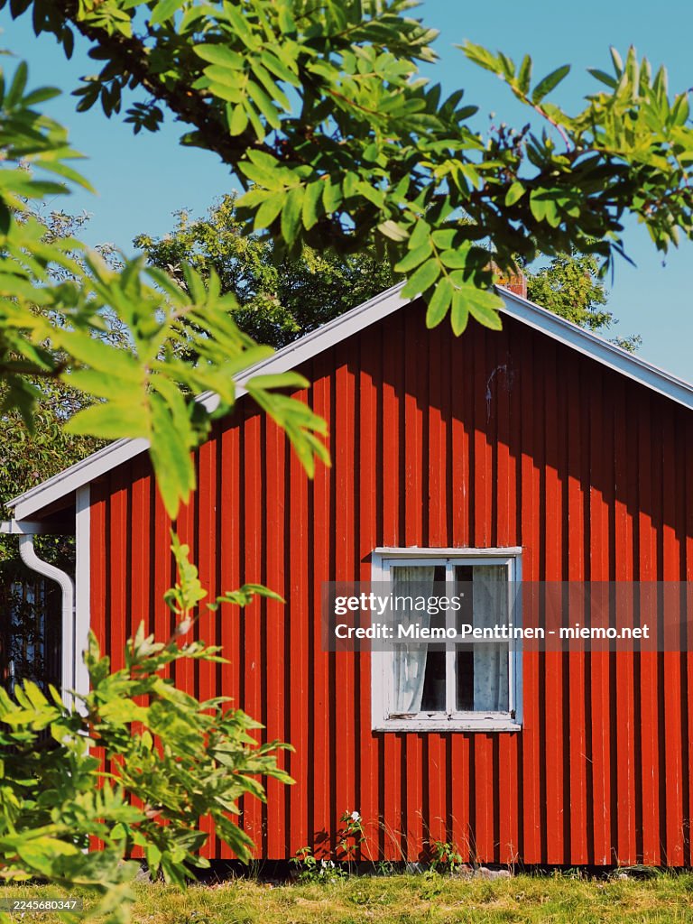 Small red wooden house with white window frame on a sunny summer day in coastal North-Western Finland
