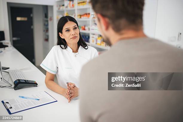 pharmacist explaining prescription to customer, patient guidance and support in pharmacy - antibiótico imagens e fotografias de stock