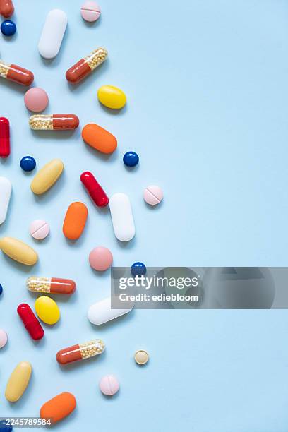 multicolored pills and tablets on blue background - pillen stockfoto's en -beelden