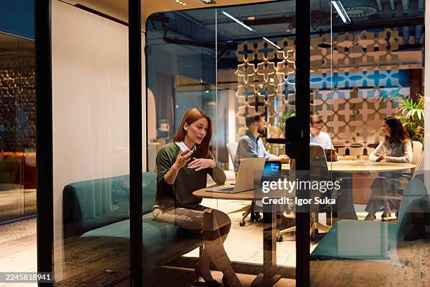 businesswoman having video call in modern office privacy pod - soundproof stock pictures, royalty-free photos & images