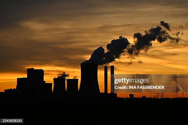 This picture taken at sunset on November 12, 2025 shows fumes rising from the cooling tower of the lignite-fired power station operated by German...