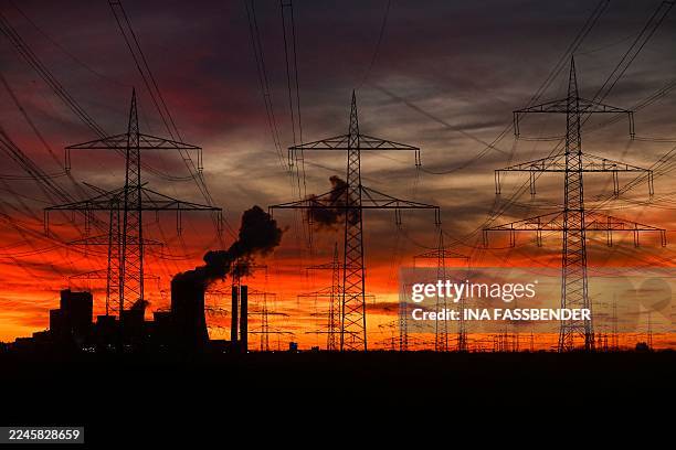 This picture taken at sunset on November 12, 2025 shows power poles near the lignite-fired power station operated by German energy giant RWE near...