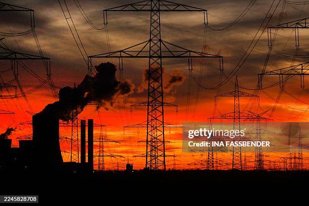 This picture taken at sunset on November 12, 2025 shows power poles near the lignite-fired power station operated by German energy giant RWE near...