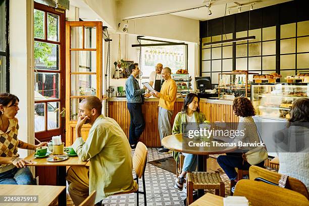 wide shot customers sitting and enjoying coffee at busy cafe - busy restaurant stock pictures, royalty-free photos & images