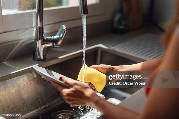 unrecognisable woman washing dishes in the sink near the window - running water stock pictures, royalty-free photos & images