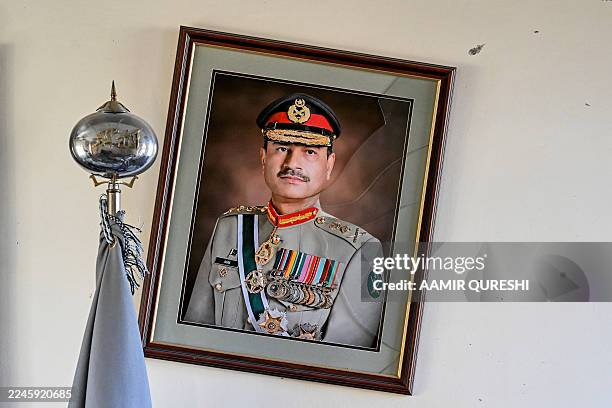 Broken frame of Pakistan's field marshal and army chief, Asim Munir, hangs on the wall after an attack at the Cadet College Wana, a military-linked...