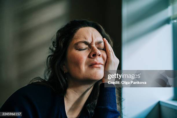woman experiencing headache pain and stress holding head - face dramatic lighting stock pictures, royalty-free photos & images