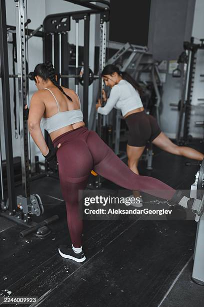 workout session in gym with two women using leg extension machines and free weights - ankle weights stock pictures, royalty-free photos & images