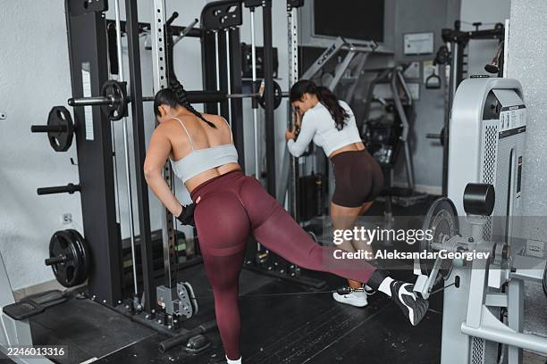 workout session in gym with two women using leg extension machines and free weights - ankle weights stock pictures, royalty-free photos & images