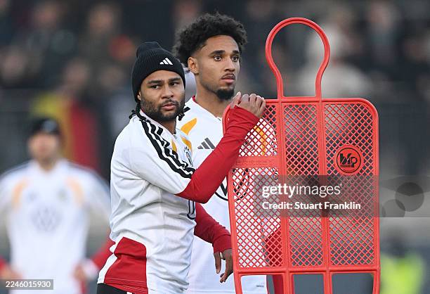 Serge Gnabry and Kevin Schade stand together during a public training session of the German national team at AOK Stadion on November 10, 2025 in...