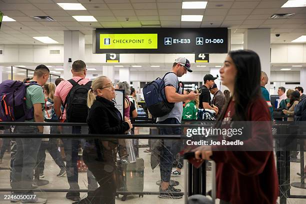 Travelers wait in line to clear through a TSA checkpoint at the Miami International Airport on November 10, 2025 in Miami, Florida. Airports have...