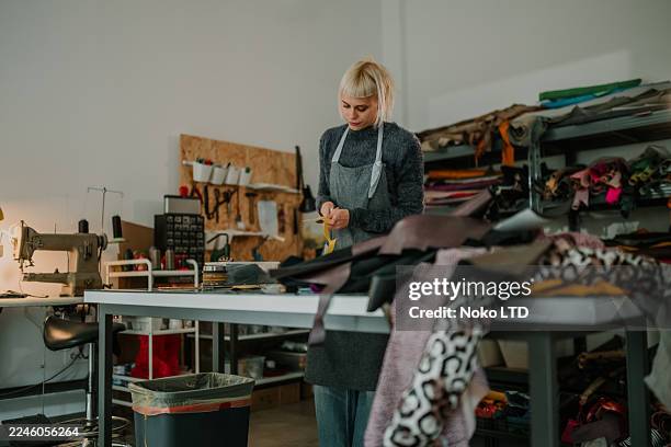woman measuring fabric in creative sewing workshop - creative space stock pictures, royalty-free photos & images