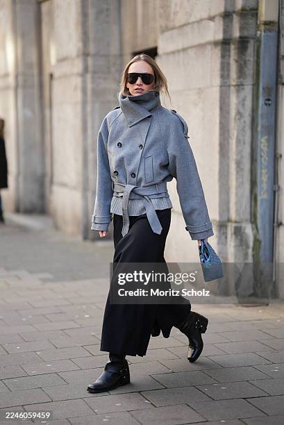 Duesseldorf, GERMANY Laura Schulte is seen wearing a grey double-breasted wool jacket with a funnel neck, wide lapels, belted waist, and buttoned...
