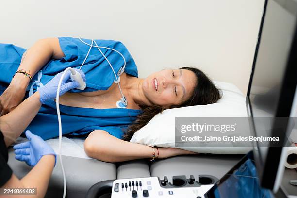 frau, die sich einer echokardiogramm-untersuchung in einer medizinischen klinik unterzieht - echokardiogramm stock-fotos und bilder