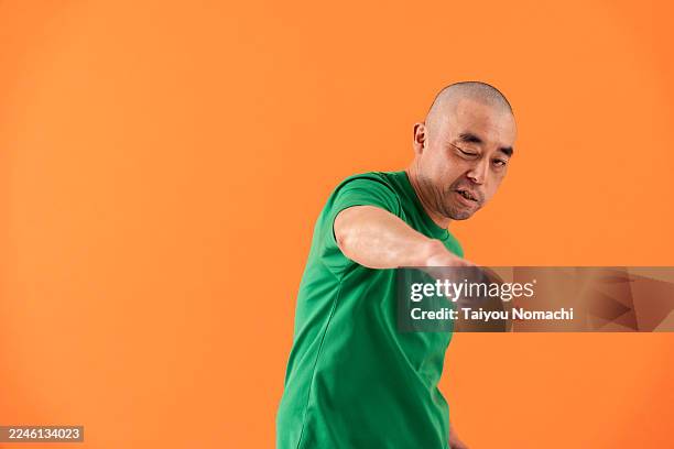 a japanese man in his 40s with left-side facial paralysis dancing in a studio setting, captured in a portrait. - neuromuscular system stock pictures, royalty-free photos & images