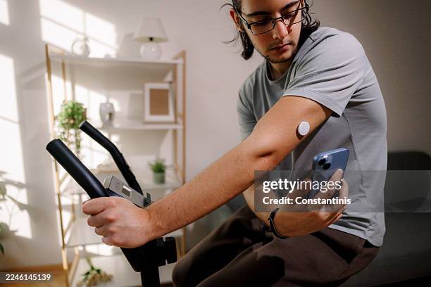 man using phone to read glucose levels from arm sensor - continuous glucose monitor stock pictures, royalty-free photos & images
