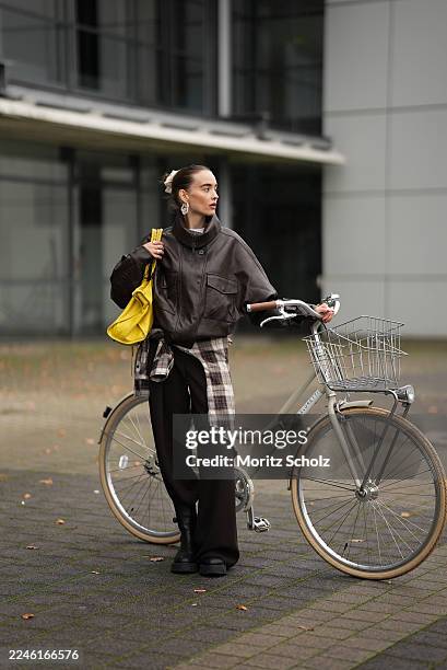 Evi Wave is seen wearing a dark brown oversized faux leather Aemmi bomber jacket with a high funnel collar, dropped shoulders, and exaggerated chest...