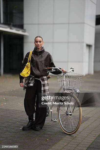 Evi Wave is seen wearing a dark brown oversized faux leather Aemmi bomber jacket with a high funnel collar, dropped shoulders, and exaggerated chest...