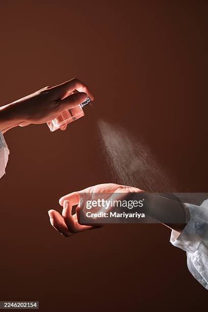 applying perfume spray to wrist for personal fragrance - perfume stock pictures, royalty-free photos & images
