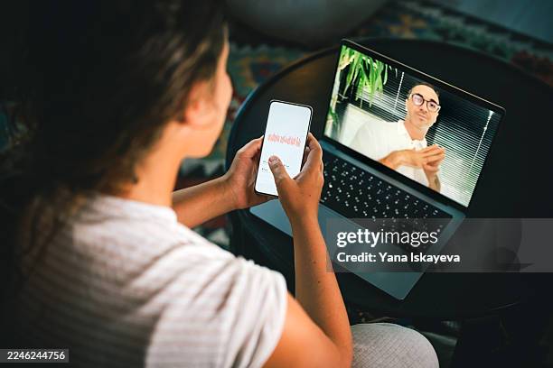 health tech at home: a beautiful woman uses a smartphone and laptop while a medical patch on the arm signals remote monitoring and telemedicine in daily life - biosensor fotografías e imágenes de stock